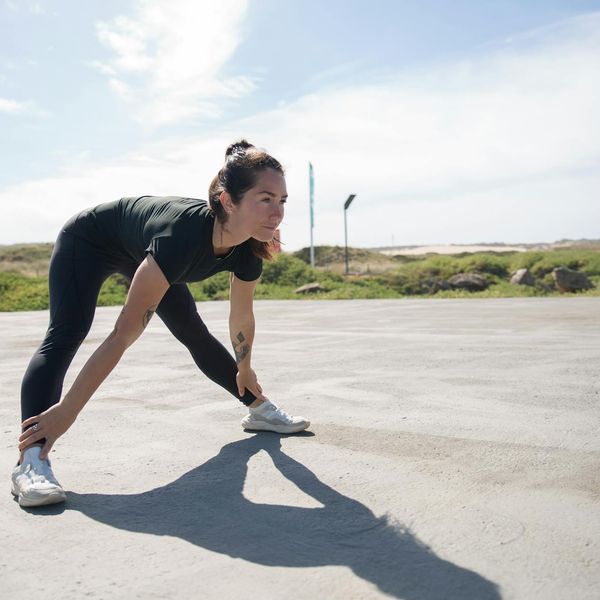 Woman smiling and stretching outdoors in a park, feeling energized.